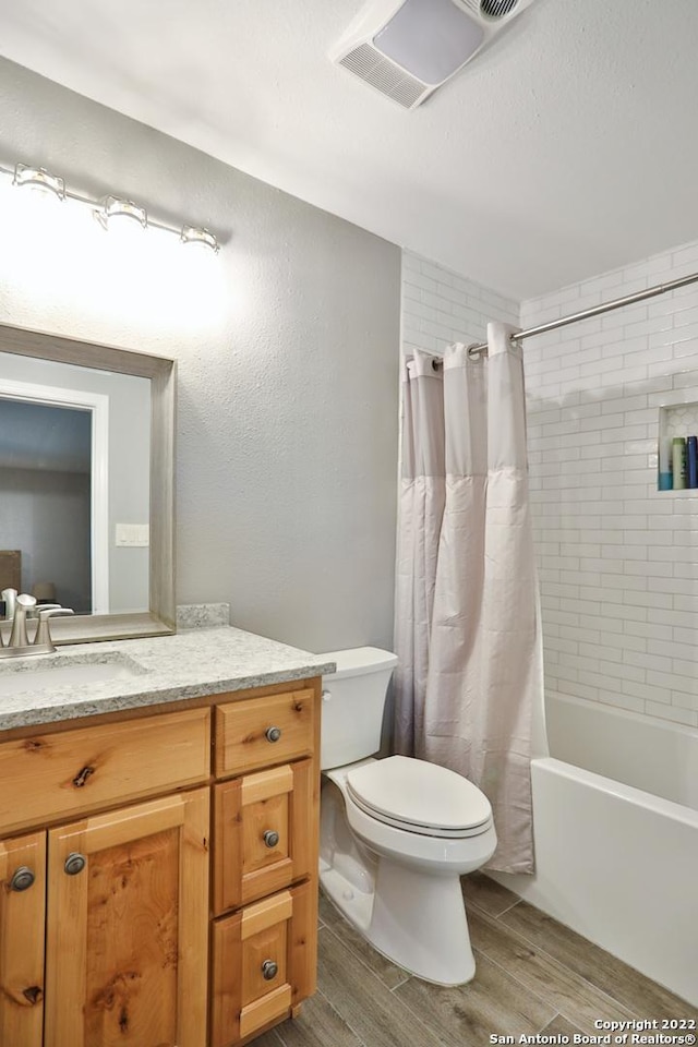 full bathroom with wood finished floors, toilet, vanity, and shower / bath combo