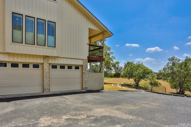 view of side of home featuring driveway, stone siding, and a garage