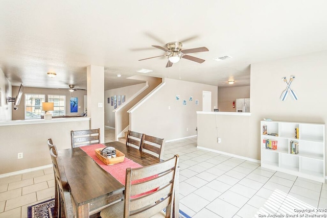 tiled dining space featuring ceiling fan, baseboards, and stairway