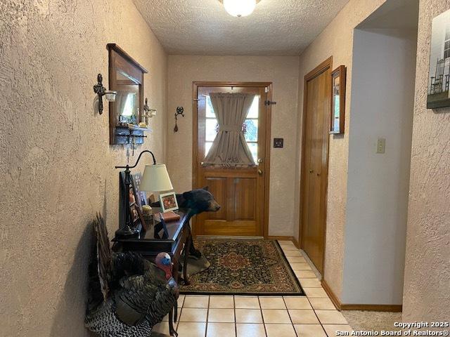 9516 Geronimo Oaks, San Antonio, TX 78254 - doorway to outside with a textured ceiling, a textured wall, and light tile patterned floors