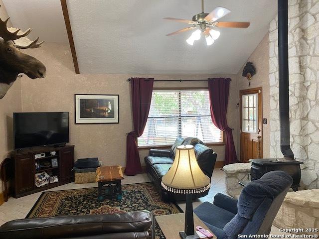 9516 Geronimo Oaks, San Antonio, TX 78254 - living room with a wood stove, vaulted ceiling, and a ceiling fan