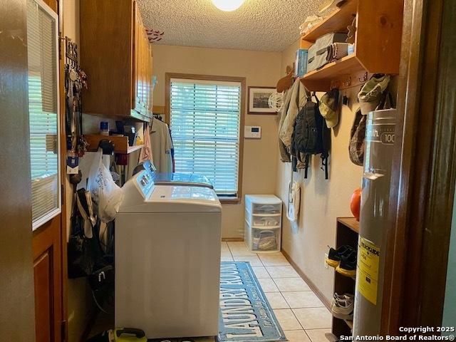 9516 Geronimo Oaks, San Antonio, TX 78254 - laundry area with washer and dryer, light tile patterned floors, cabinet space, a textured ceiling, and healthy amount of natural light