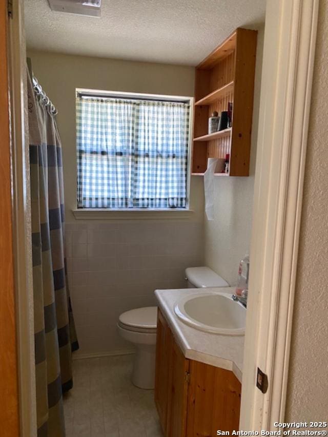 9516 Geronimo Oaks, San Antonio, TX 78254 - bathroom with toilet, vanity, a textured ceiling, and curtained shower