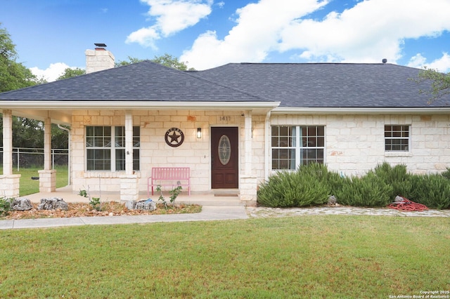 ranch-style home featuring roof with shingles, covered porch, a chimney, a front lawn, and stone siding