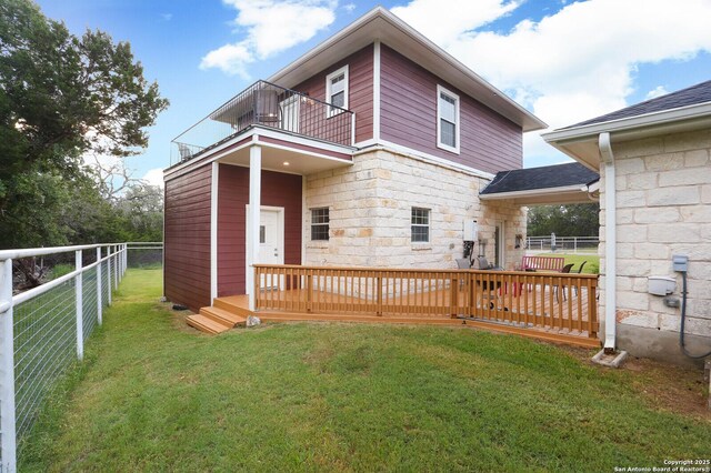 rear view of house featuring a balcony, stone siding, a deck, and roof with shingles