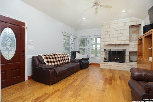 living room featuring light wood-type flooring, ceiling fan, a stone fireplace, recessed lighting, and lofted ceiling