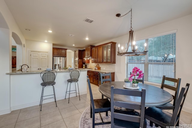 dining space featuring a chandelier, light tile patterned floors, arched walkways, recessed lighting, and baseboards