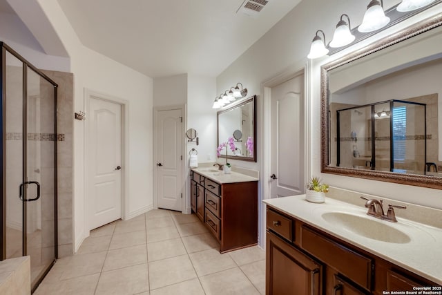 bathroom with tile patterned floors, a shower stall, and two vanities