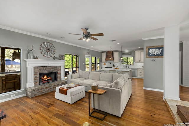 16222 Deer Crst, San Antonio, TX 78248 - living room with a brick fireplace, a ceiling fan, hardwood / wood-style floors, baseboards, and crown molding