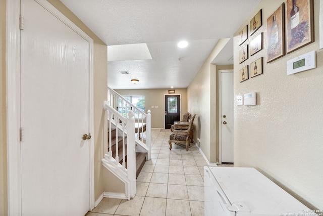 13303 Sunset Rainbow, San Antonio, TX 78245 - corridor with stairs, light tile patterned flooring, a textured ceiling, baseboards, and a textured wall