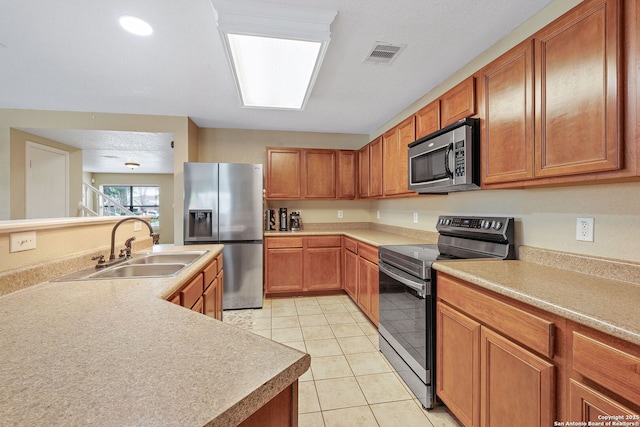 13303 Sunset Rainbow, San Antonio, TX 78245 - kitchen featuring stainless steel appliances, a sink, light tile patterned floors, brown cabinets, and light countertops