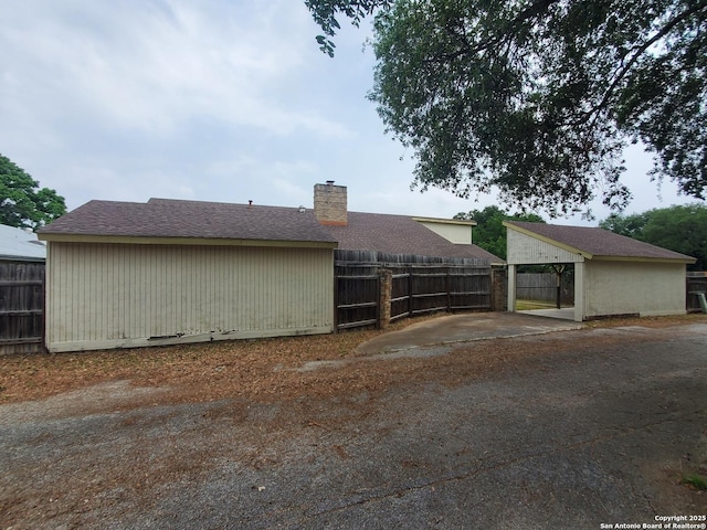 view of side of home featuring fence and a chimney