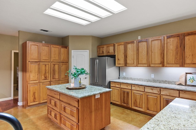 1200 Brand, Bulverde, TX 78163 - kitchen with freestanding refrigerator, light stone counters, a kitchen island, and brown cabinets