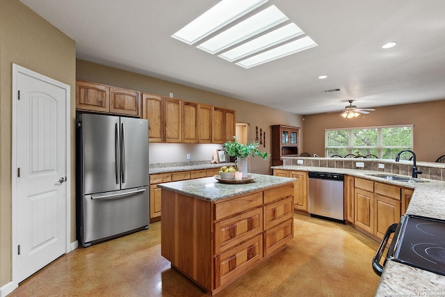 1200 Brand, Bulverde, TX 78163 - kitchen featuring appliances with stainless steel finishes, a kitchen island, a sink, light stone countertops, and a skylight