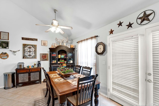 dining space featuring a ceiling fan, vaulted ceiling, light tile patterned flooring, and baseboards