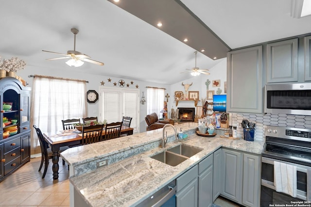 kitchen featuring appliances with stainless steel finishes, ceiling fan, a sink, a peninsula, and vaulted ceiling