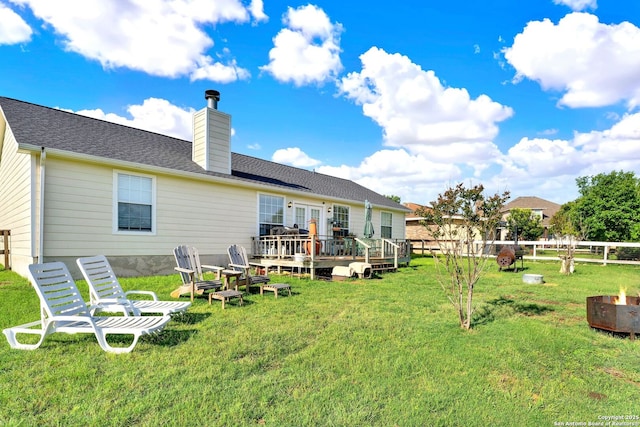 back of house with a wooden deck, a fire pit, and a chimney