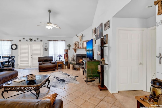 living room with a ceiling fan, light tile patterned floors, lofted ceiling, and a fireplace