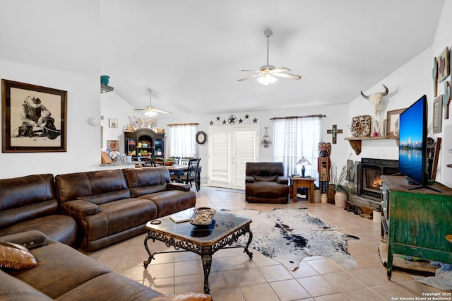 living room featuring a stone fireplace, a ceiling fan, lofted ceiling, and light tile patterned floors