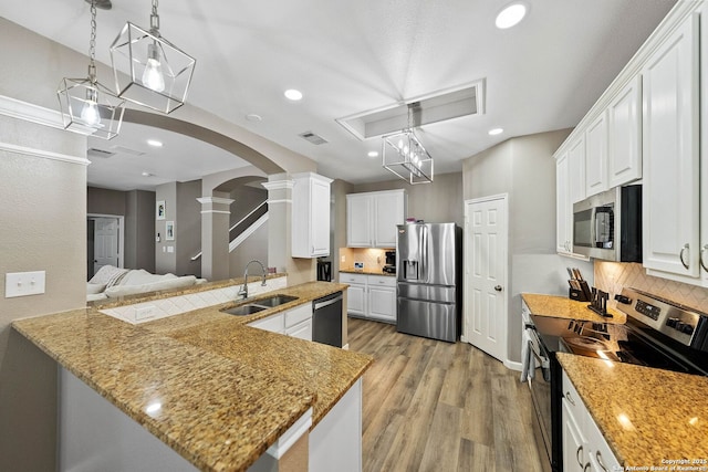 kitchen with appliances with stainless steel finishes, a sink, decorative columns, arched walkways, and decorative backsplash