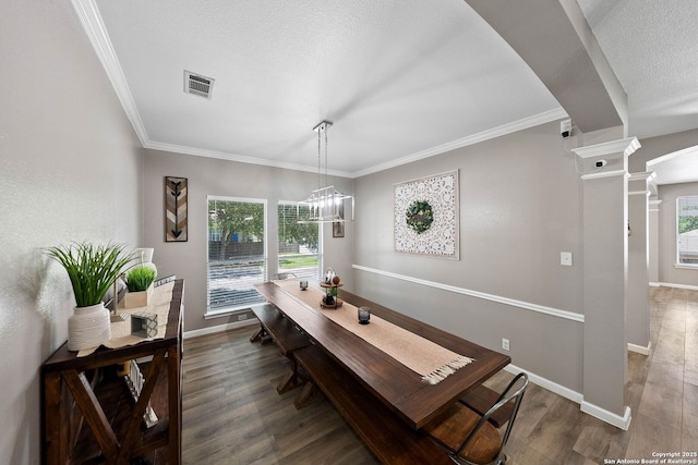 dining space featuring ornate columns, wood finished floors, crown molding, baseboards, and a textured ceiling