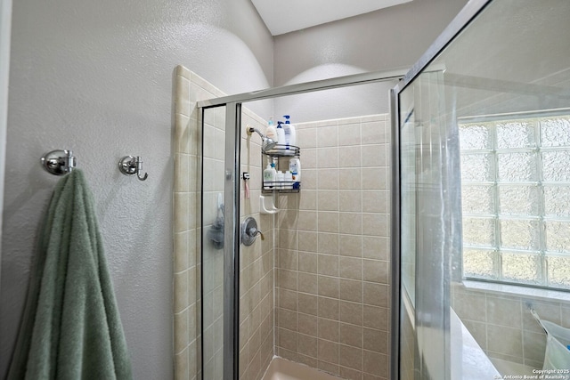 bathroom with a textured wall and a stall shower
