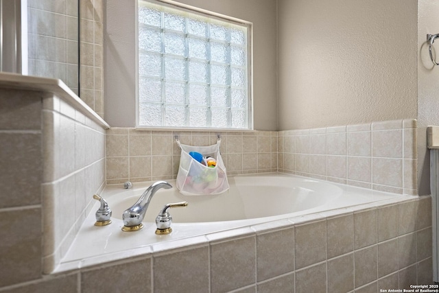 bathroom with a textured wall and a garden tub