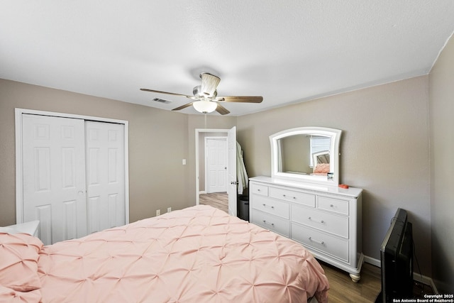 bedroom featuring wood finished floors, a closet, a ceiling fan, and baseboards