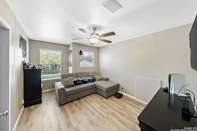 living area featuring ceiling fan, light wood-style floors, and baseboards