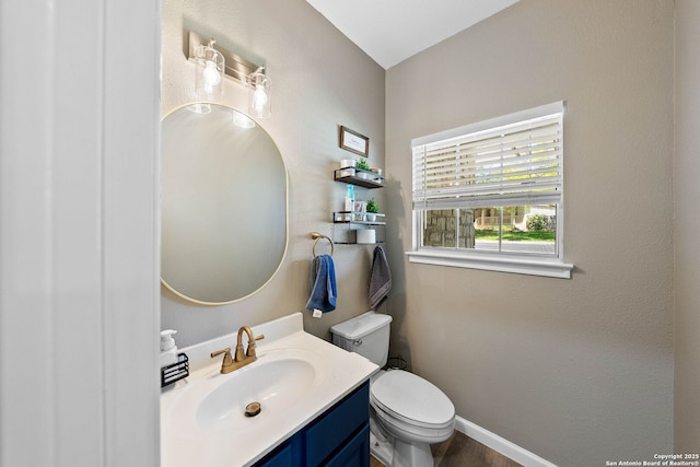 half bath with toilet, vanity, and baseboards