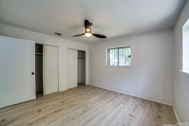 2114 S Trinity St, San Antonio, TX 78207 - unfurnished bedroom featuring two closets, light wood-style flooring, ceiling fan, and baseboards