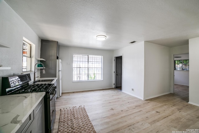 2114 S Trinity St, San Antonio, TX 78207 - kitchen featuring black range with gas stovetop, freestanding refrigerator, a sink, light wood-style floors, and healthy amount of natural light