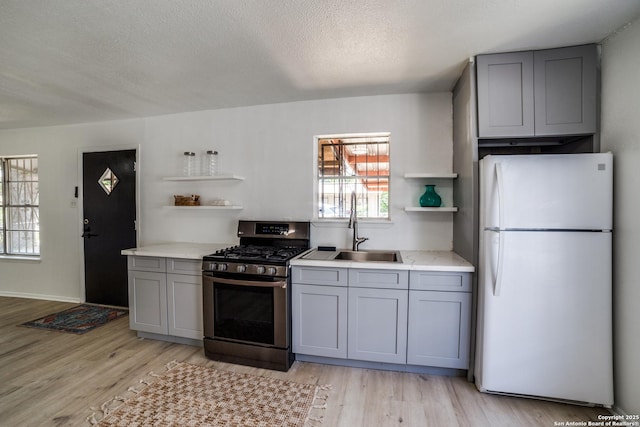 2114 S Trinity St, San Antonio, TX 78207 - kitchen featuring freestanding refrigerator, stainless steel range with gas cooktop, gray cabinets, open shelves, and a textured ceiling