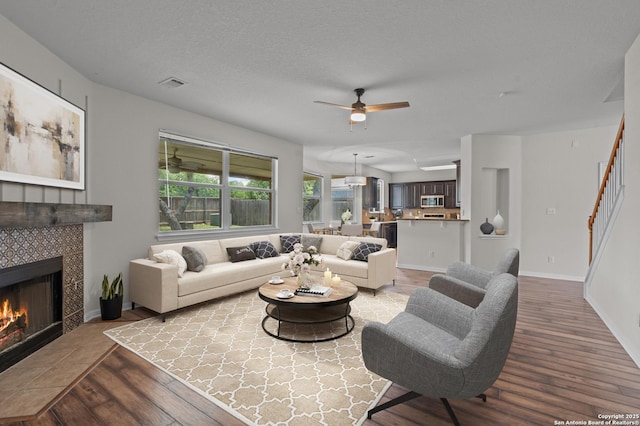 25836 Stone Cyn, San Antonio, TX 78260 - living room with wood finished floors, ceiling fan, a tile fireplace, and stairway