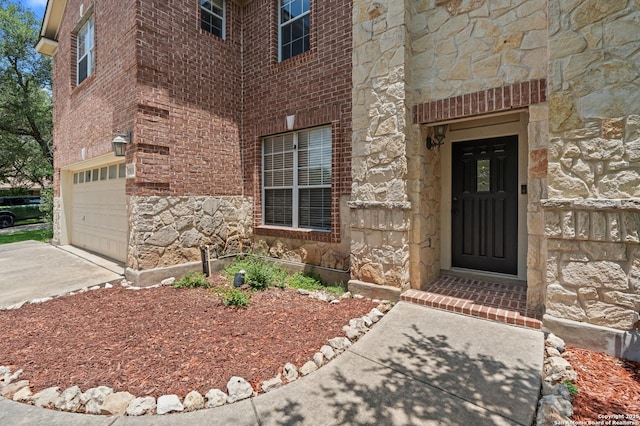 25836 Stone Cyn, San Antonio, TX 78260 - view of exterior entry featuring stone siding, an attached garage, driveway, and brick siding