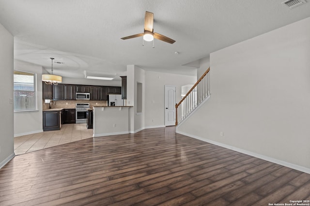 25836 Stone Cyn, San Antonio, TX 78260 - unfurnished living room featuring light wood finished floors, a ceiling fan, stairs, and a textured ceiling
