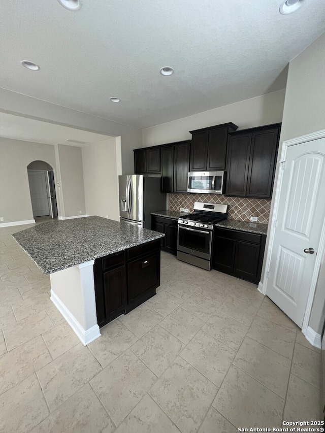 17339 Brachetto, San Antonio, TX 78247 - kitchen with stainless steel appliances, arched walkways, backsplash, dark cabinets, and dark stone countertops