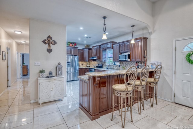 333 Studer, Uvalde, TX 78801 - kitchen with appliances with stainless steel finishes, decorative backsplash, a peninsula, light stone counters, and a kitchen breakfast bar
