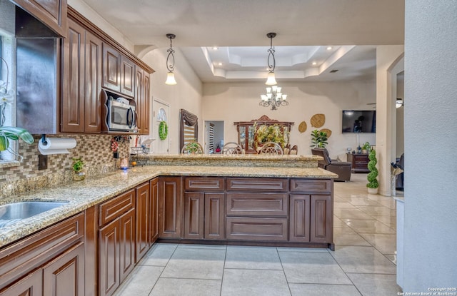 333 Studer, Uvalde, TX 78801 - kitchen with a tray ceiling, a peninsula, tasteful backsplash, stainless steel microwave, and a chandelier