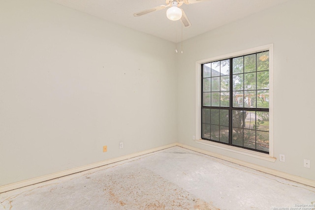 empty room featuring a ceiling fan, concrete flooring, and baseboards