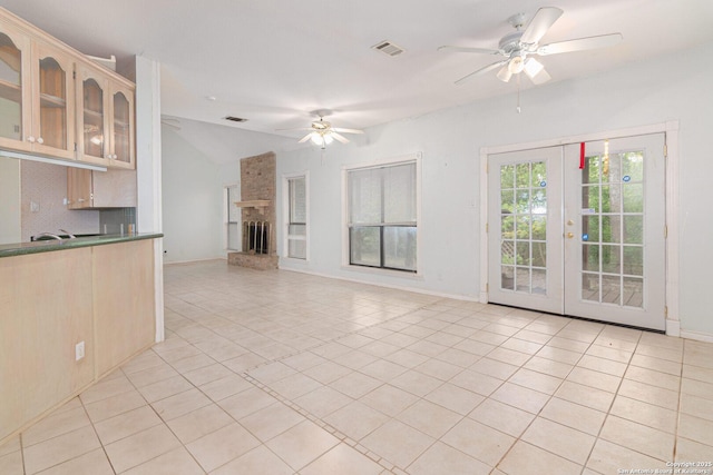 unfurnished living room featuring ceiling fan, light tile patterned floors, vaulted ceiling, baseboards, and french doors