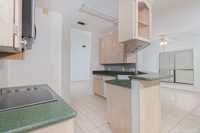 kitchen featuring white dishwasher, a sink, a peninsula, light tile patterned floors, and light brown cabinetry