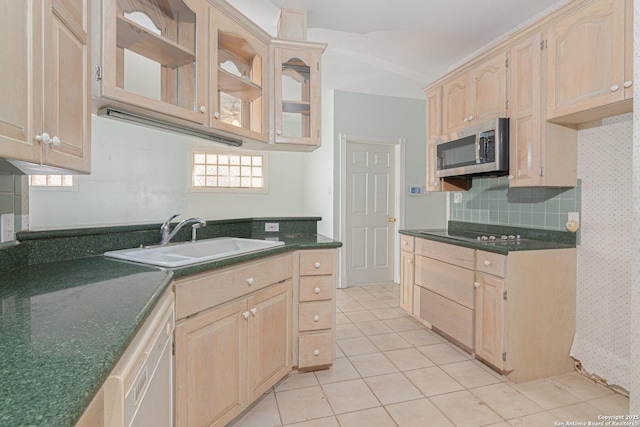 kitchen featuring stainless steel microwave, a sink, light brown cabinets, dark countertops, and wallpapered walls