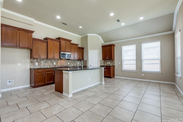 12418 Maverick Rnch, San Antonio, TX 78254 - kitchen featuring stainless steel microwave, decorative backsplash, brown cabinets, light tile patterned floors, and an island with sink