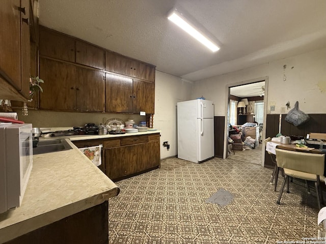 318 Uvalde, San Antonio, TX 78210 - kitchen with freestanding refrigerator, light countertops, dark brown cabinetry, and a textured ceiling