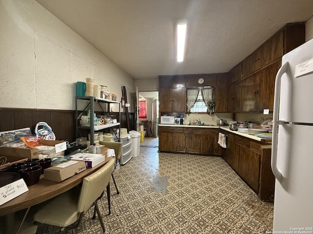 318 Uvalde, San Antonio, TX 78210 - kitchen featuring white appliances, light countertops, wainscoting, dark brown cabinetry, and wood walls