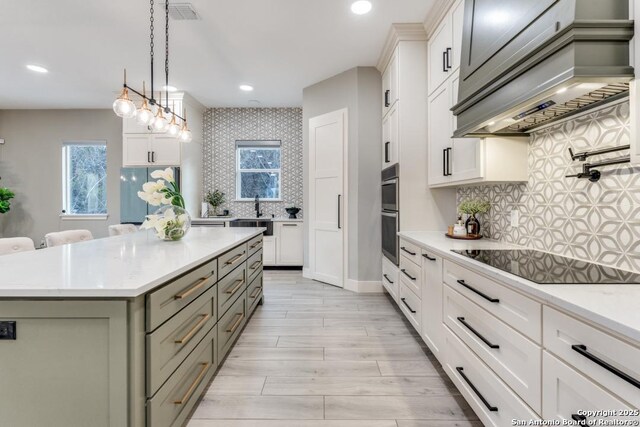 7812 Ventura Blvd, Selma, TX 78154 - kitchen with black electric cooktop, light countertops, custom range hood, a kitchen island, and tasteful backsplash