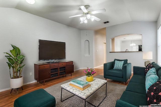 living area with lofted ceiling, wood finished floors, a ceiling fan, baseboards, and arched walkways