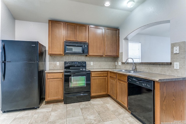 kitchen featuring black appliances, decorative backsplash, a sink, arched walkways, and light countertops