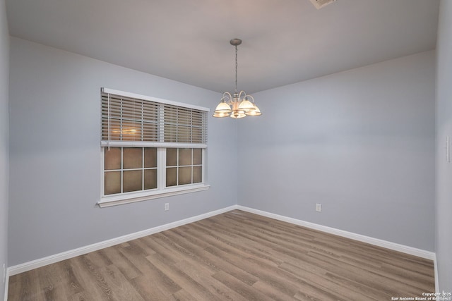 7603 Braun Bnd, San Antonio, TX 78250 - spare room featuring wood finished floors, a chandelier, and baseboards
